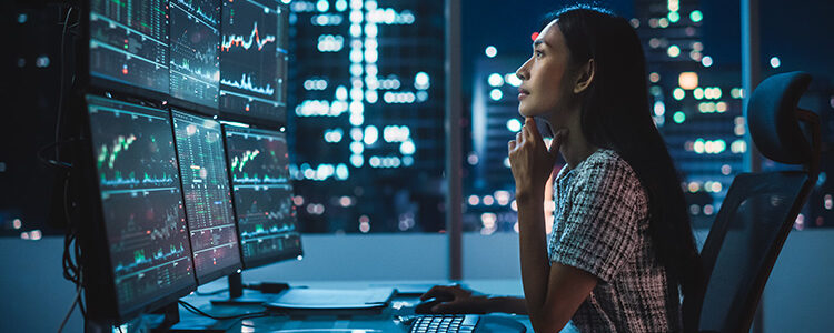Retrato de uma Analista Financeira Trabalhando em um Computador com Estação de Trabalho Multi-Monitor com Gráficos de Ações, Commodities e Mercado de Câmbio em Tempo Real.