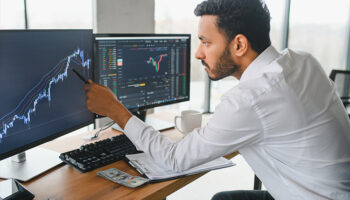 Retrato de um investidor bem-sucedido analisando gráficos da bolsa de valores na tela do computador.